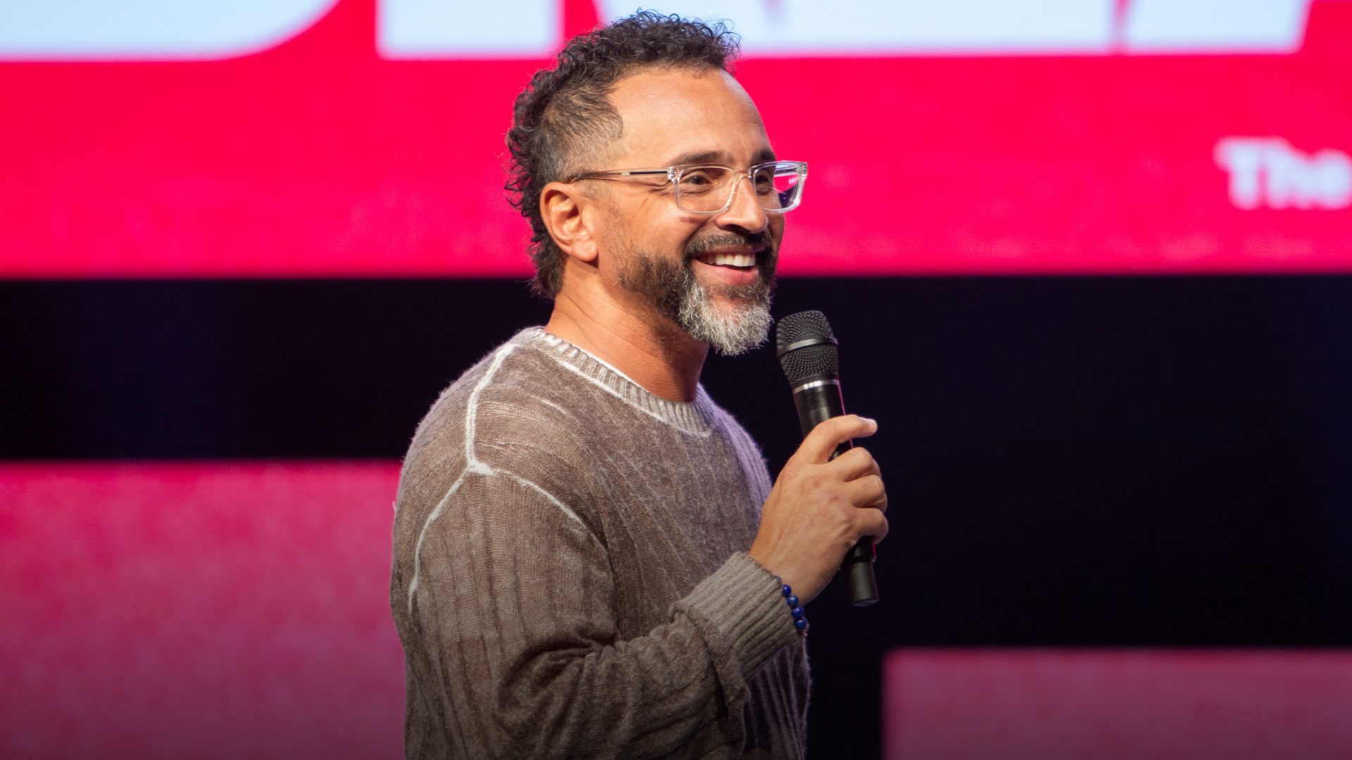 Pastor Tony smiling and speaking into a microphone on stage